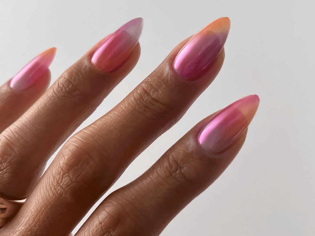 5 Chrome Nail Art Designs You Have to Try This Season 6 A close-up of a hand showcasing long, elegant nails with a shimmering pink ombré effect, blending into soft gradient tones.